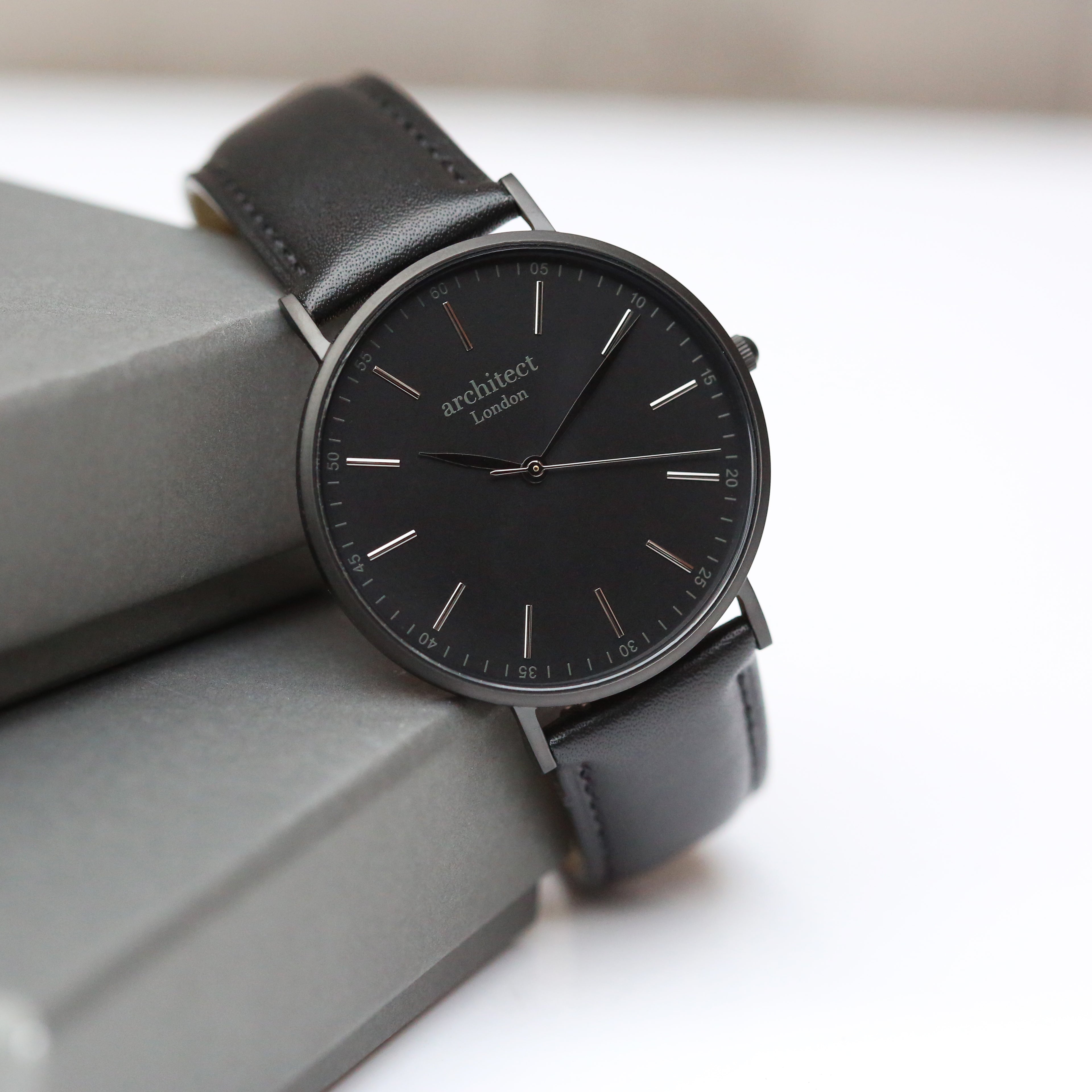 Black engraved at the back watch with leather strap on a light gray surface