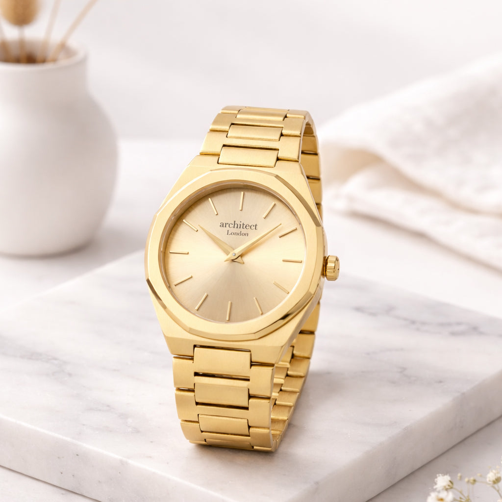 Gold wristwatch on a marble surface with a soft white background