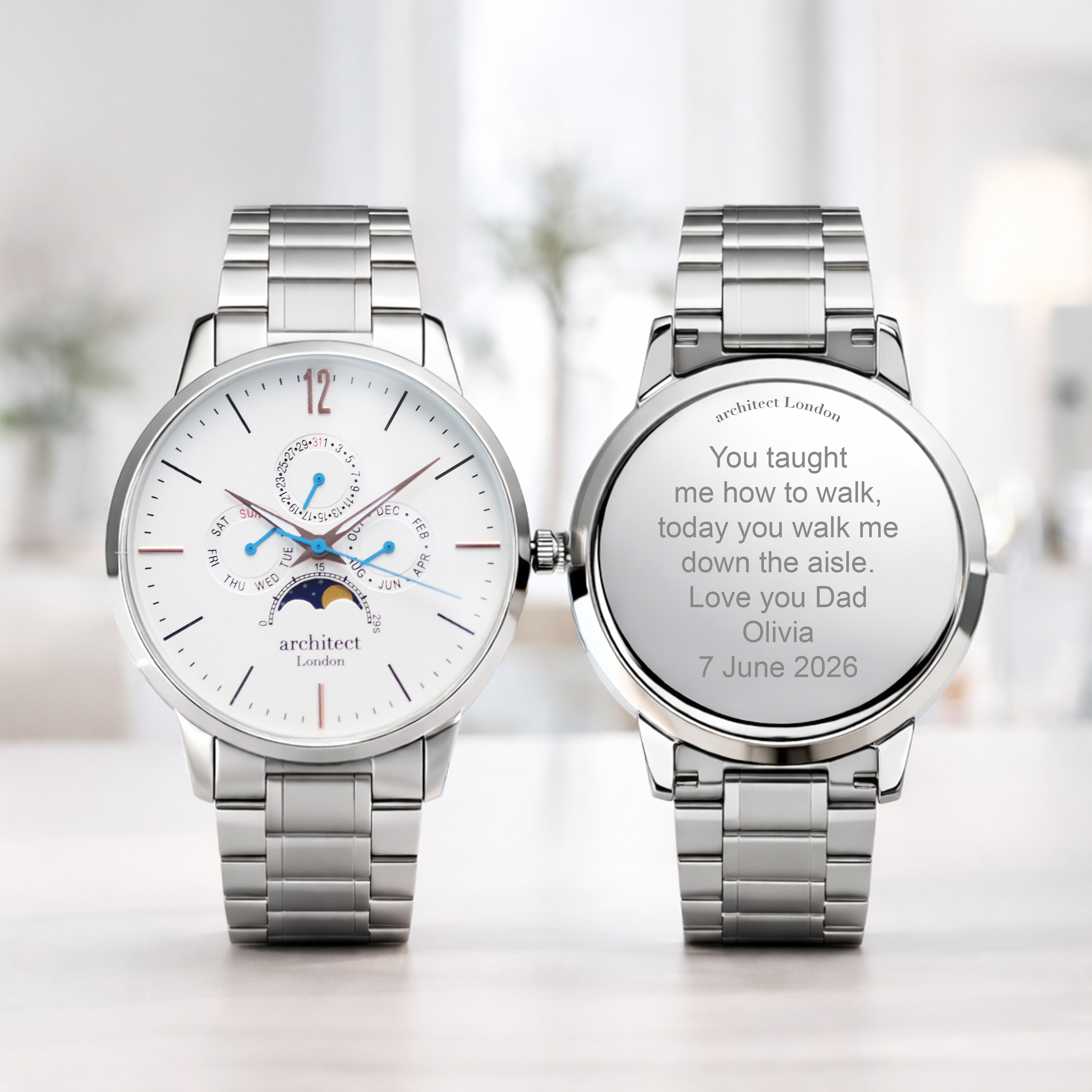 Two silver watches on a light background. One watch showing engraved text