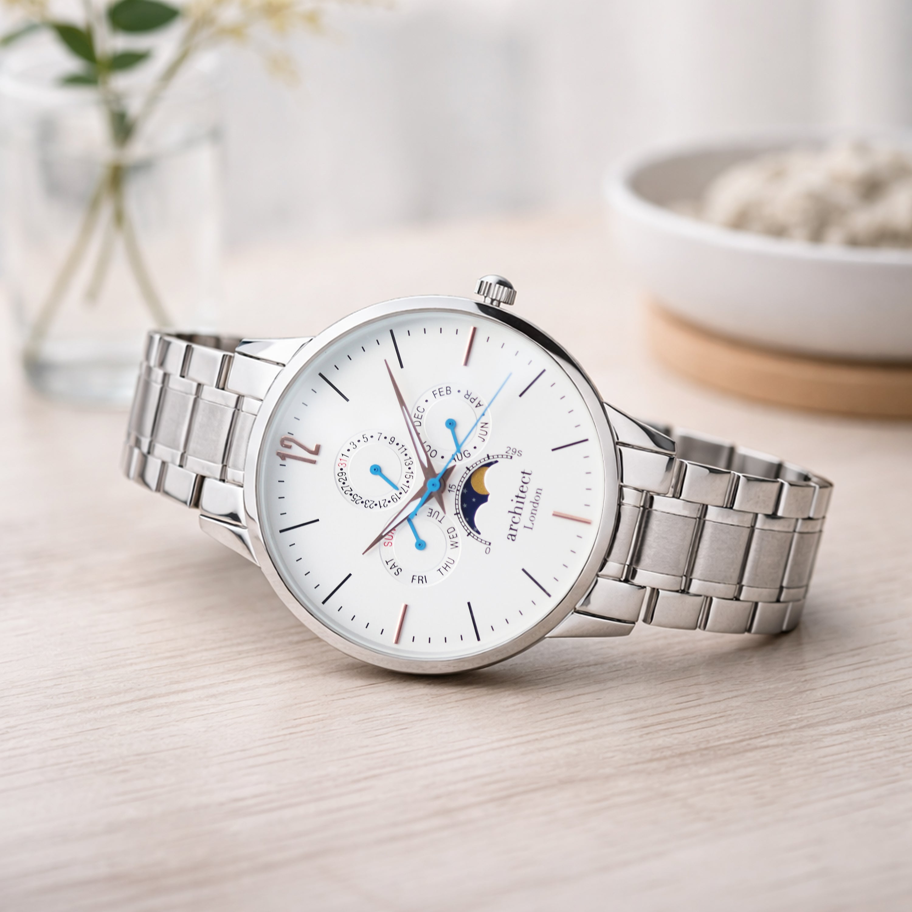 Silver wristwatch with a detailed face on a light wooden surface. Egraved watch