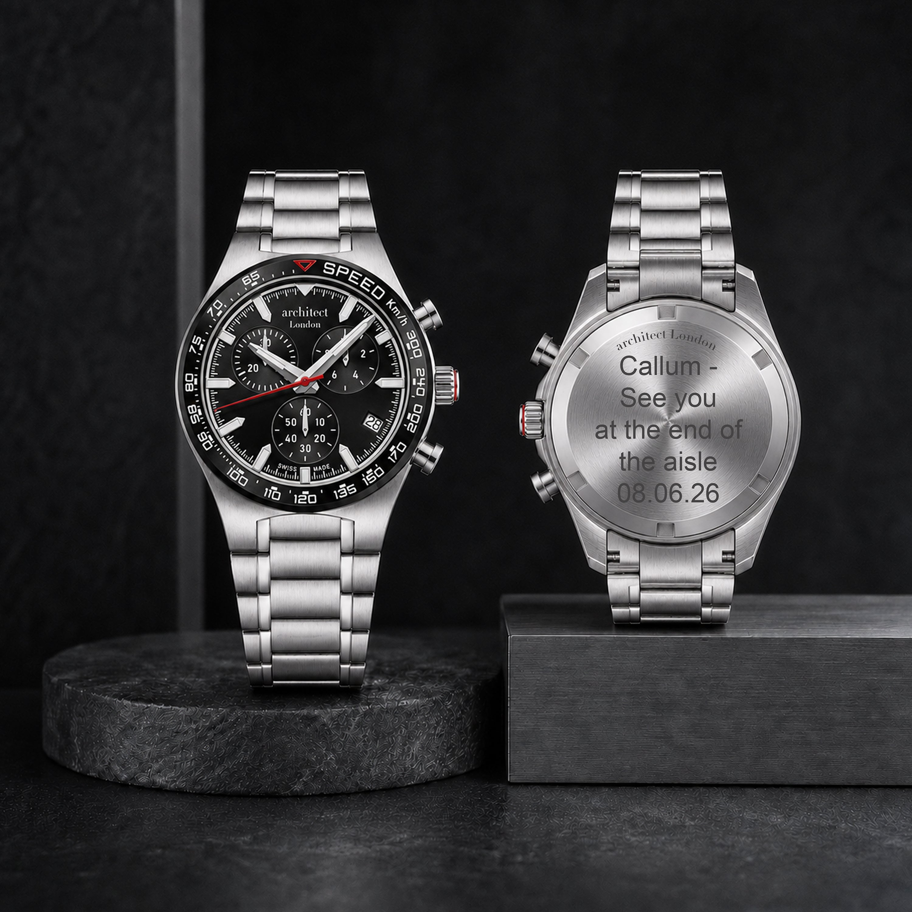 Two silver watches on black stands with engraved text on a dark background