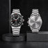 Two silver watches on black stands with engraved text on a dark background
