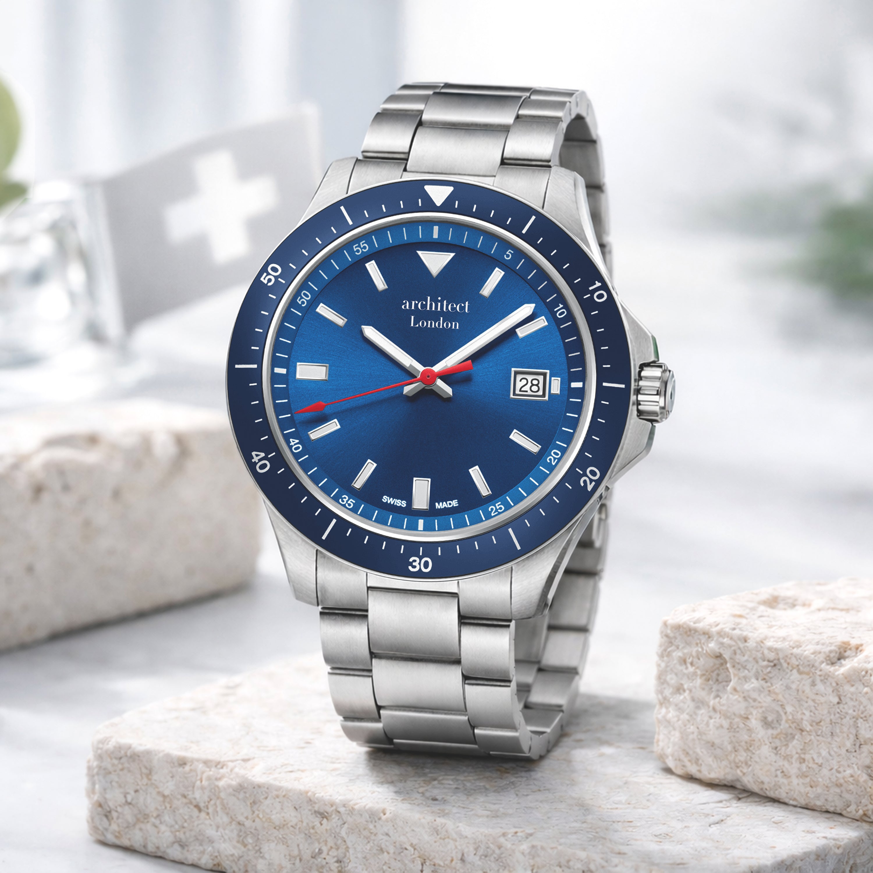 Silver watch with a blue dial on a light stone surface