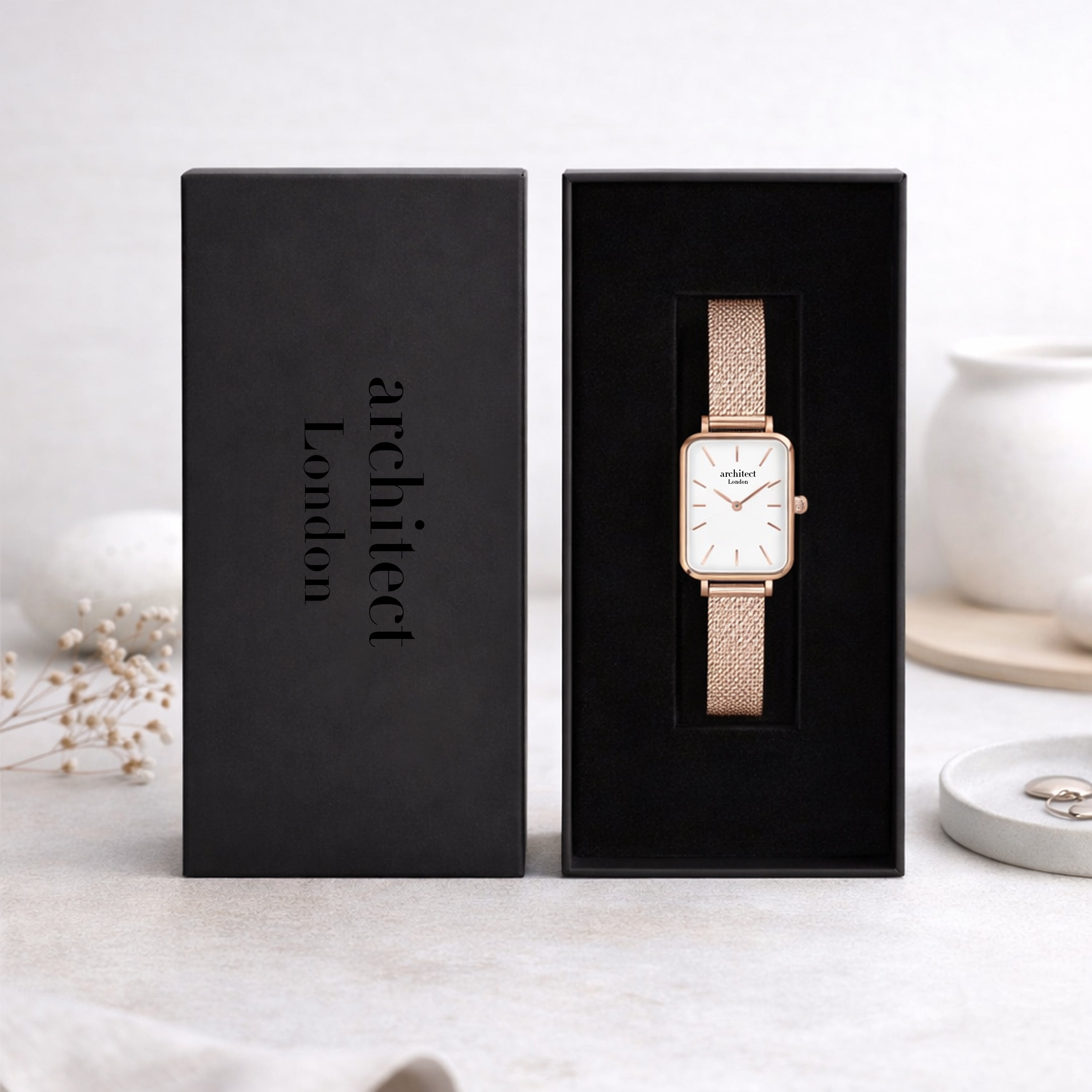 Gold watch in a black box with 'architect London' branding on a light background