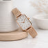 Rose gold watch with white face on a light wooden surface
