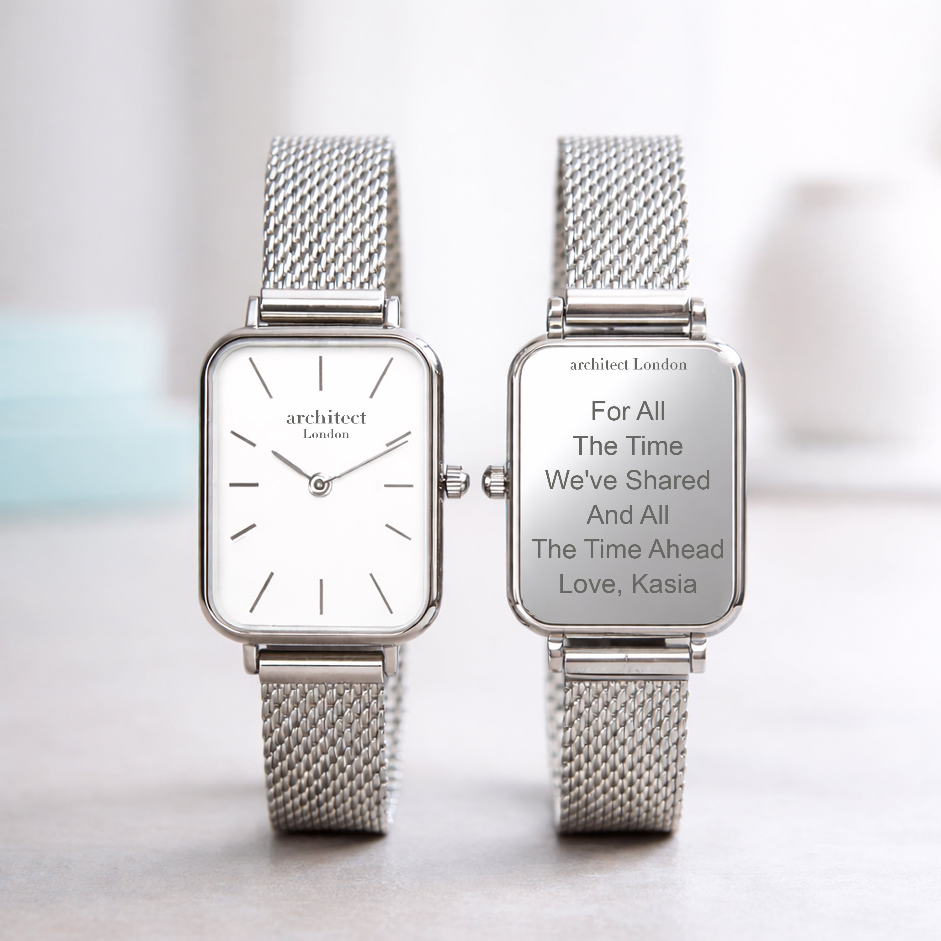 Two silver watches with mesh straps on a light background