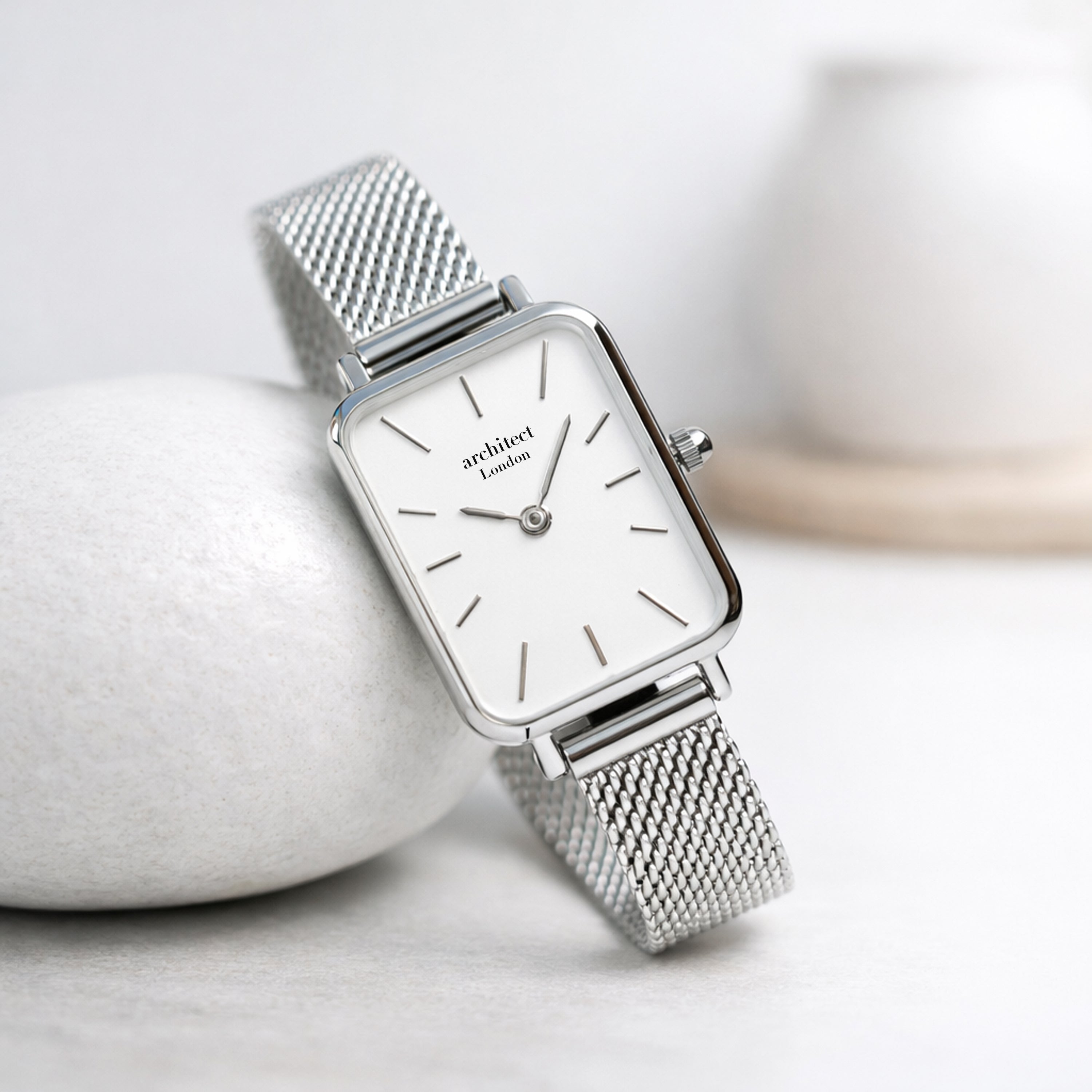 Silver watch with mesh band on a light background