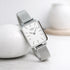 Silver watch with mesh band on a light background