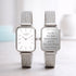 Two silver watches with mesh straps on a light background