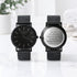Two black wristwatches on a light surface with a blurred background. One watch is personalised 