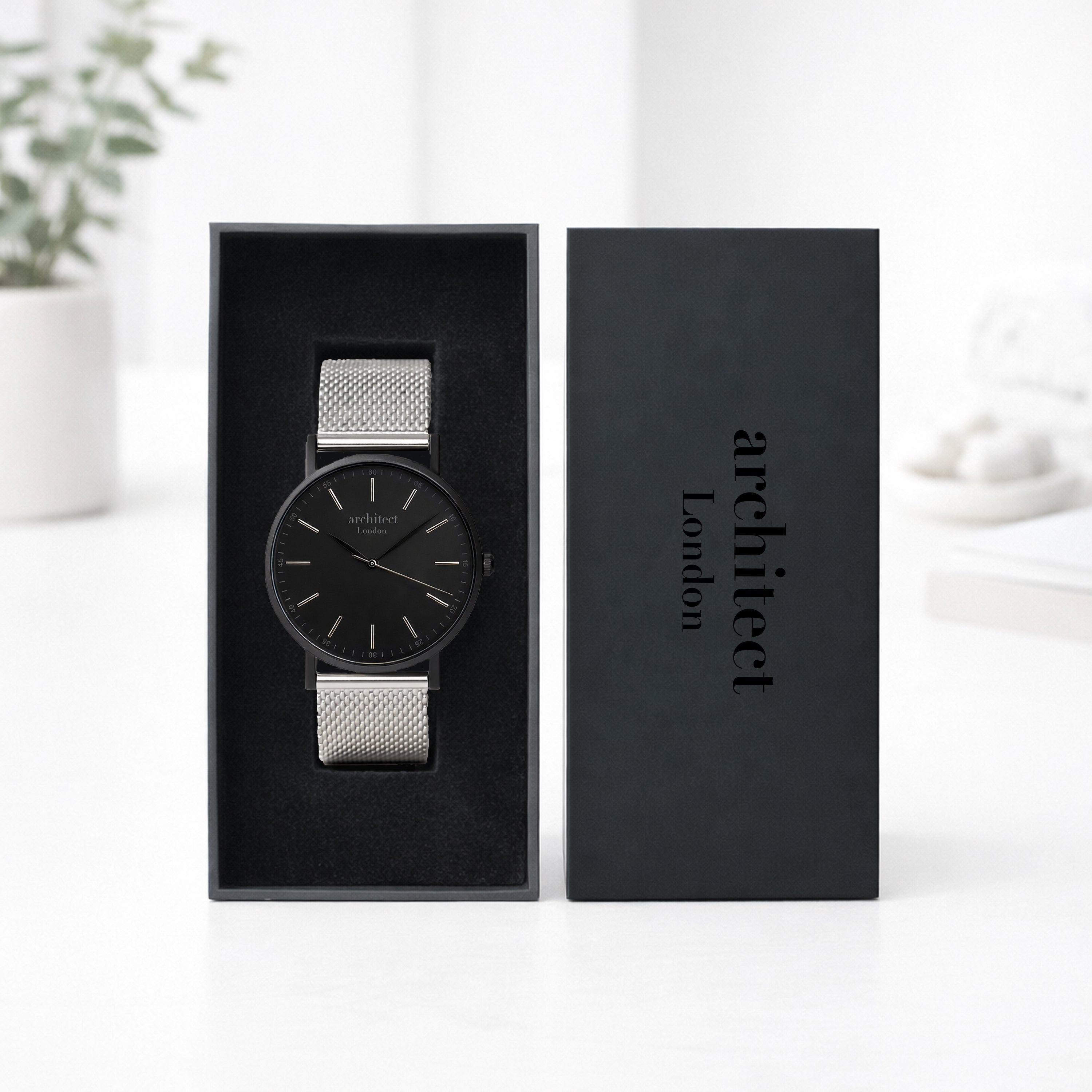 Black watch with silver mesh strap in a black box labeled 'architect London' on a white background.