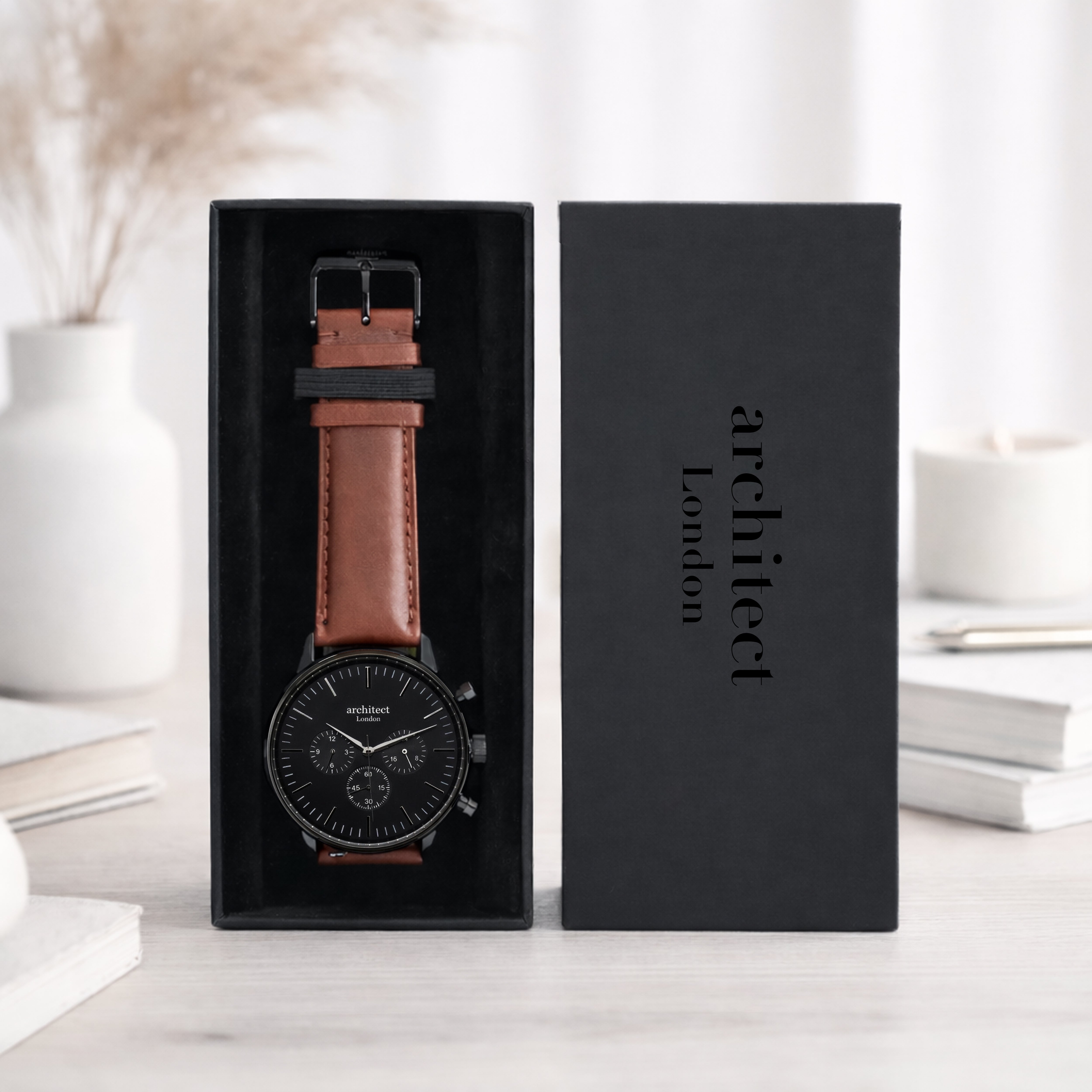 Watch with brown leather strap in a black box labeled 'architect London' on a light background.