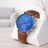 Watch with blue face and brown leather strap on a white stand