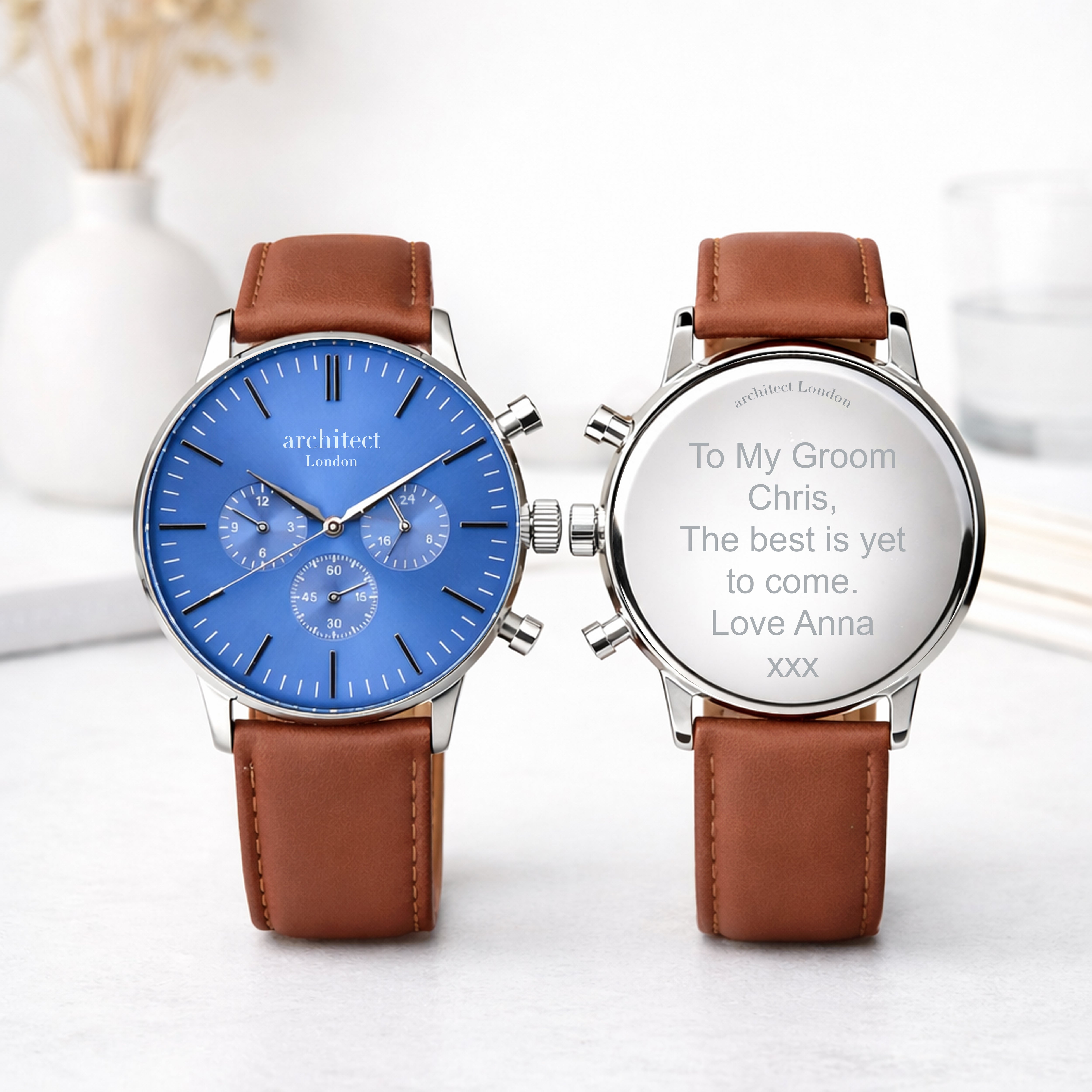 Two watches with brown leather straps and engraved messages on a white background