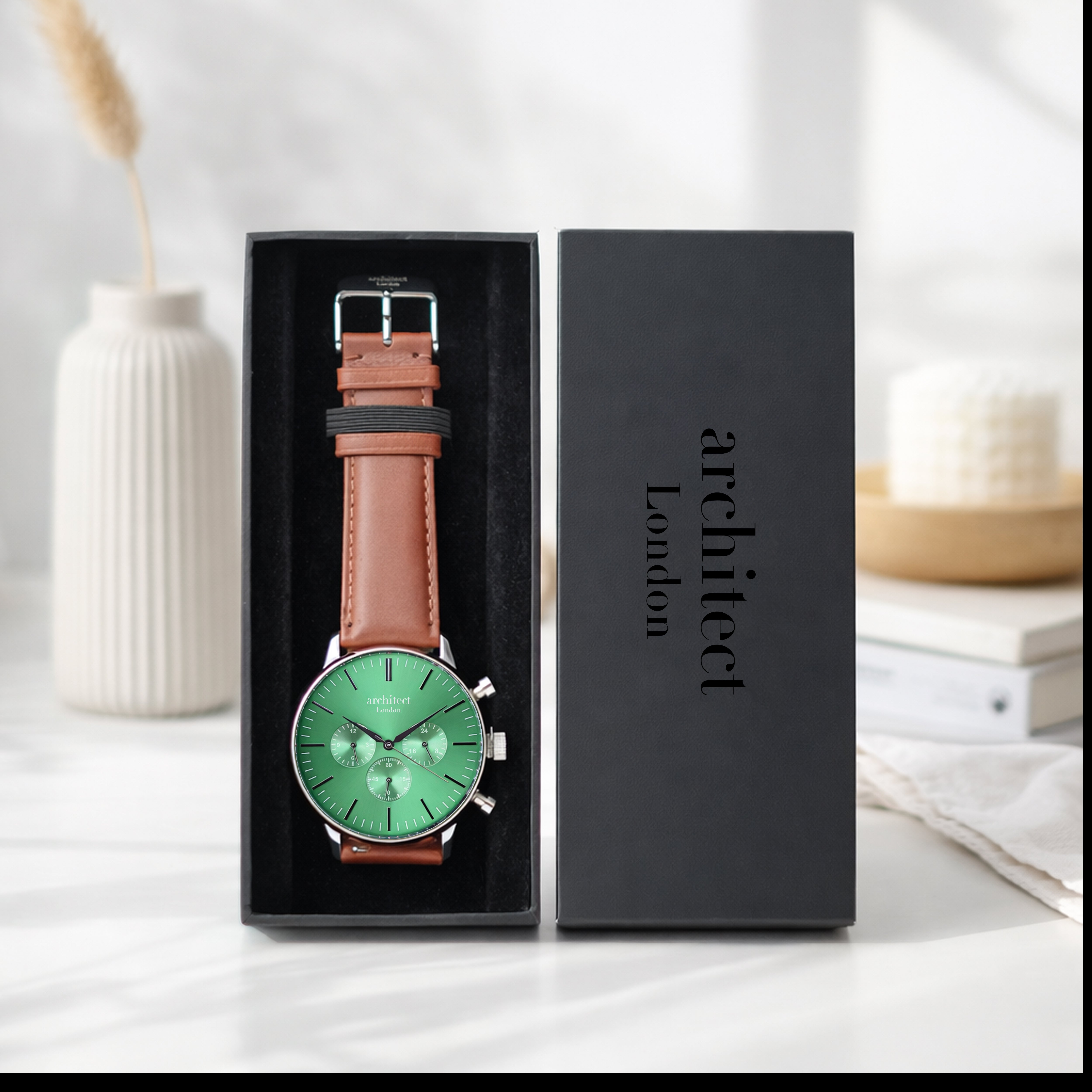 Watch with brown leather strap and green face in a black box, brand 'architect London' visible