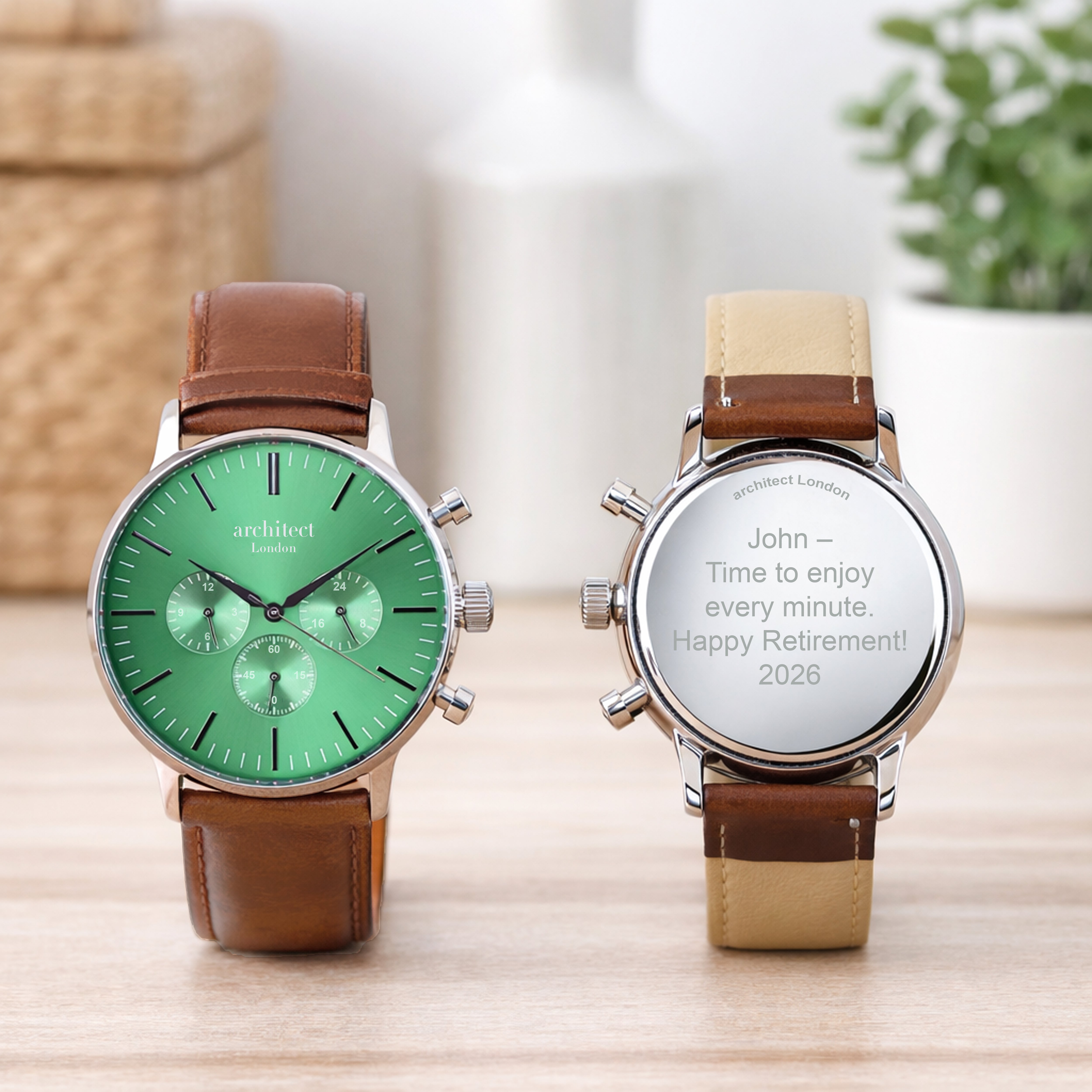 Two engraved watches with green and beige faces on a wooden surface.