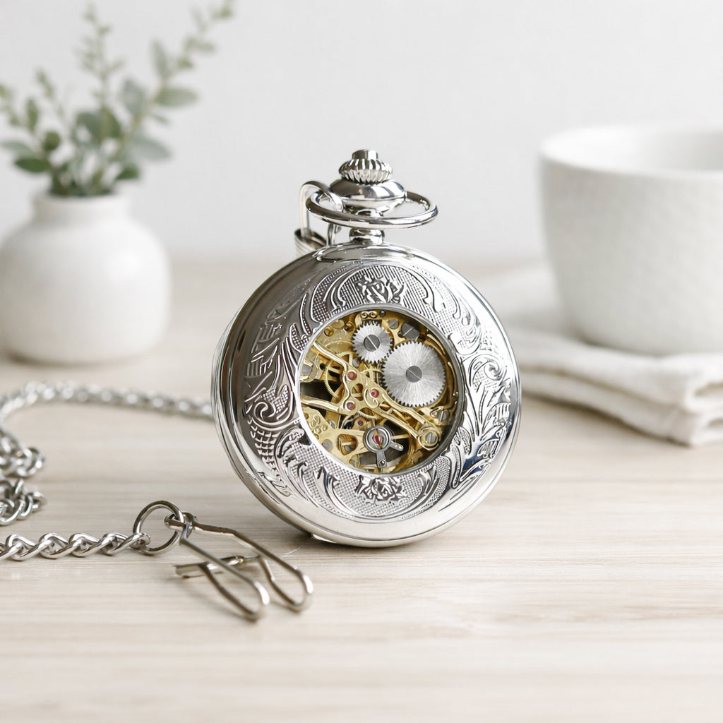 Silver pocket watch with intricate design on a light wooden surface
