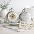 Two silver pocket watches with engraved messages on a light surface.