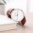 Personalised watch with a brown leather strap on a stack of books with a blurred background