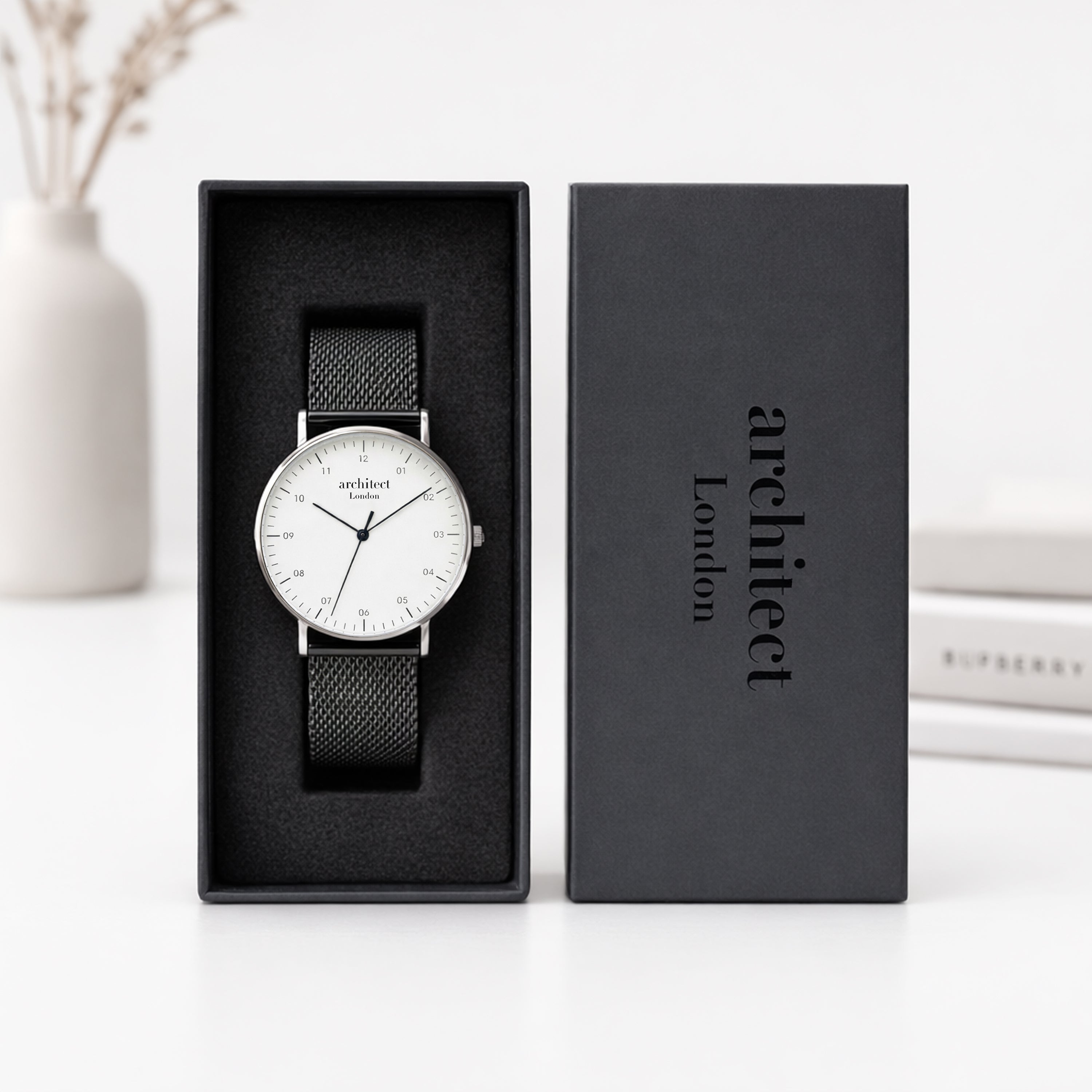 Watch with black strap in a 'Architect London' box on a white surface.